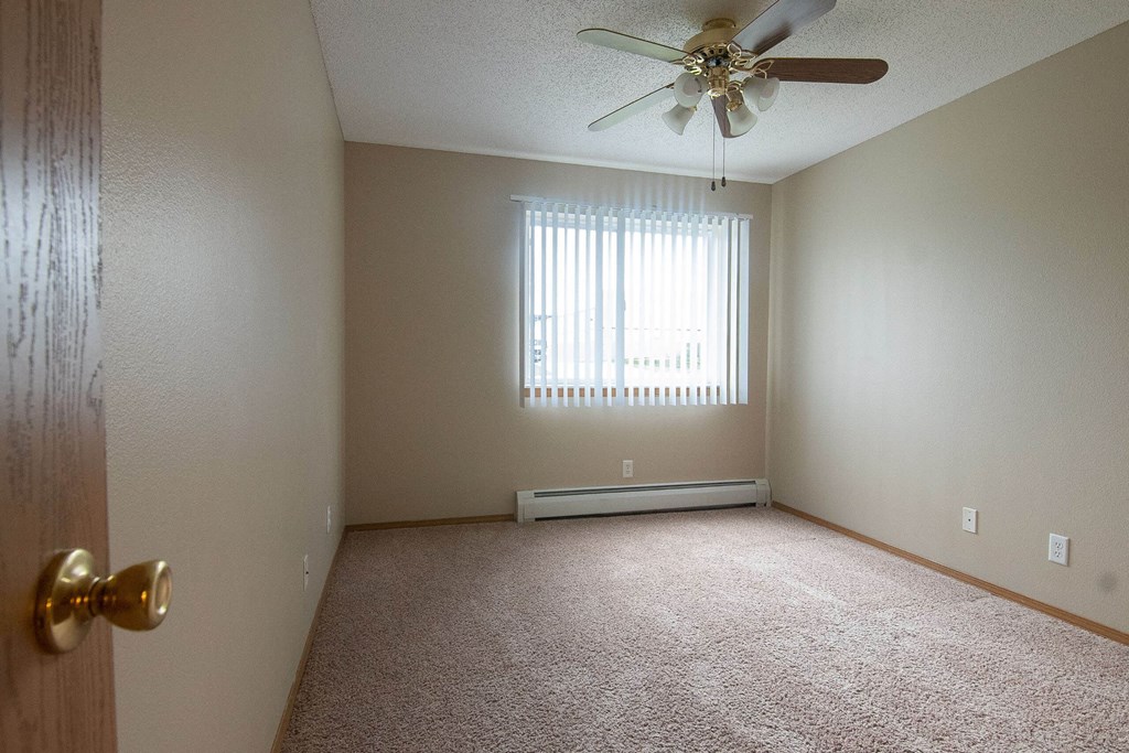 A room with a ceiling fan and a window with blinds. A room with a ceiling fan and a window with blinds at Peach Tree Apartments, Iowa, 50021
