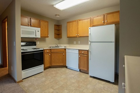 A kitchen with a white refrigerator, white oven, and brown cabinets.