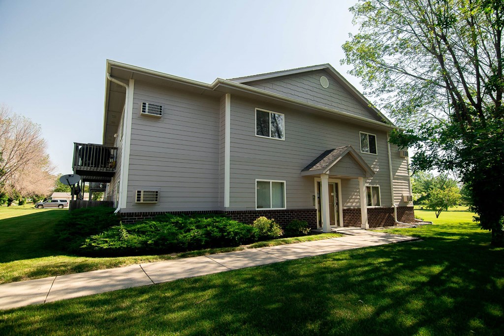 A house with a grey siding and a small porch at Peach Tree Apartments, IA, 50021