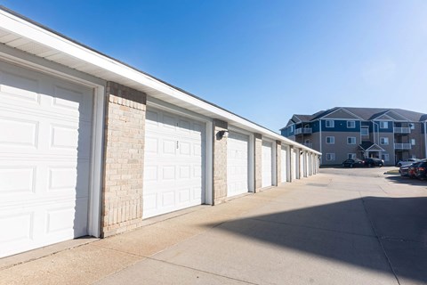 A row of white garage doors in front of a building.