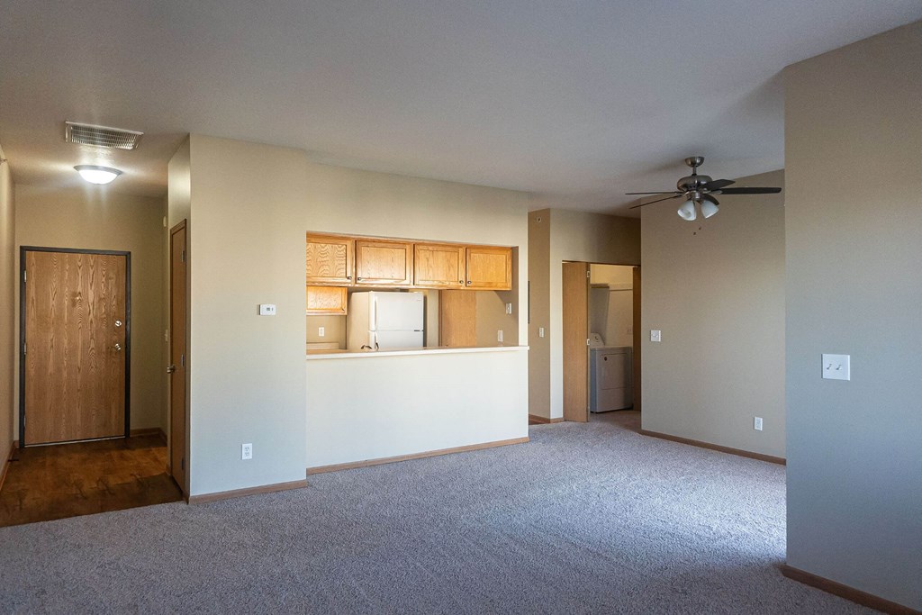 an empty living room with a kitchen and a ceiling fan an empty living room with a kitchen and a ceiling fan at Sunrise Meadows, Waukee, IA
