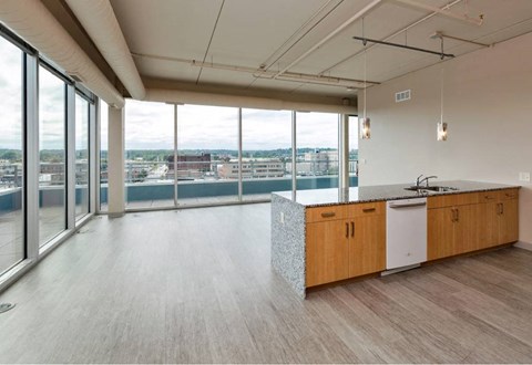A modern kitchen with wooden cabinets and a large window overlooking the city.