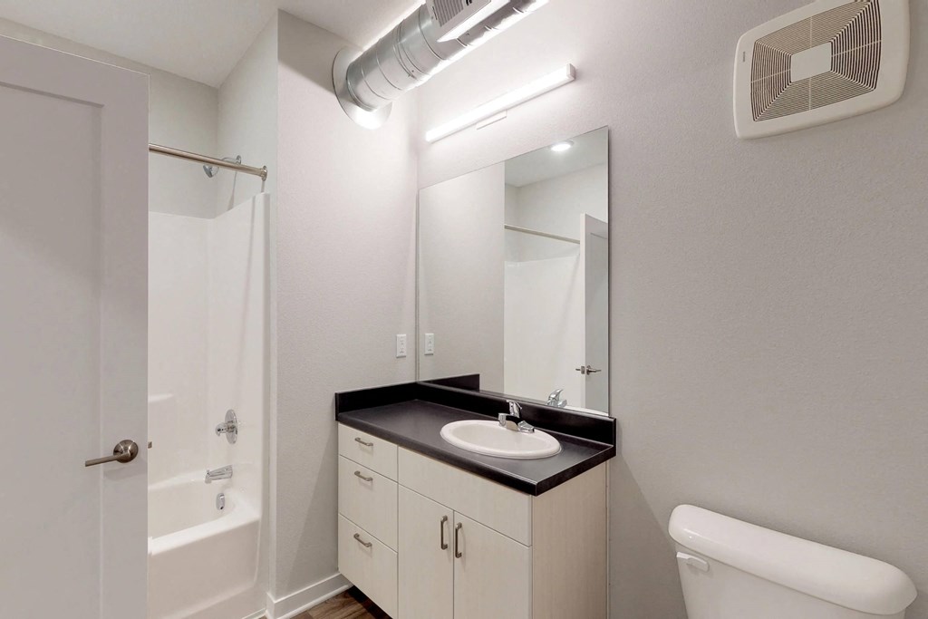 A bathroom with a sink, mirror, and toilet at Vue Apartments, IA, 50309