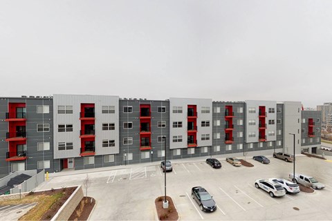 A large grey building with red accents and a parking lot in front at Vue Apartments, Des Moines