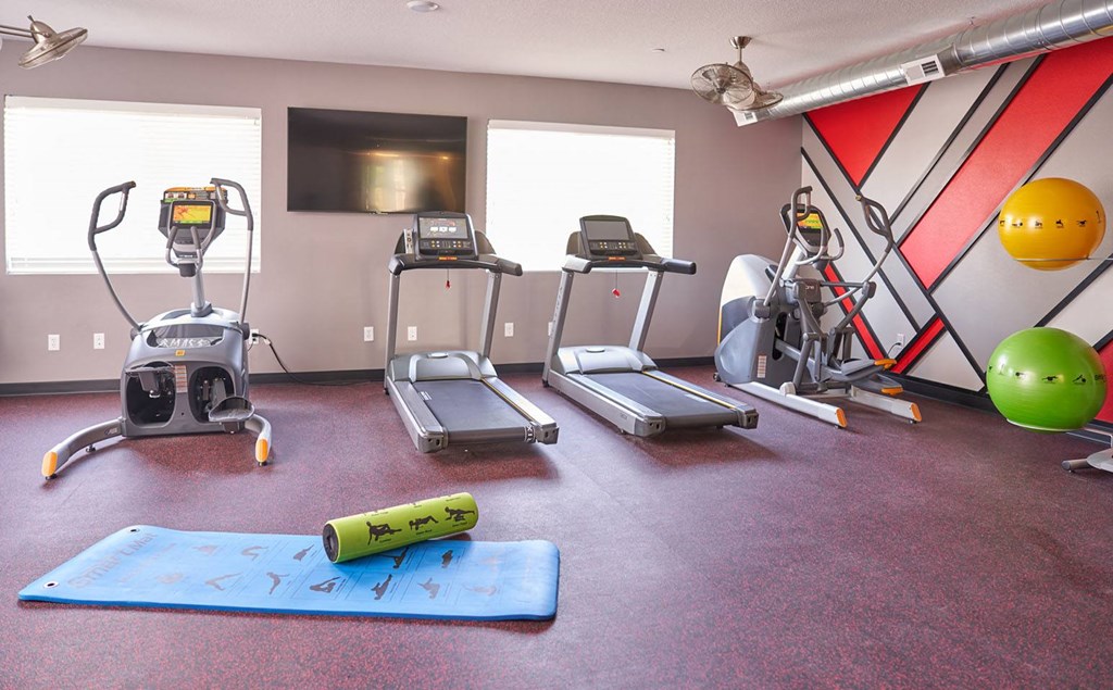 a gym with exercise equipment and weights on the floor a gym with exercise equipment and weights on the floor at Vue Apartments, Des Moines, Iowa
