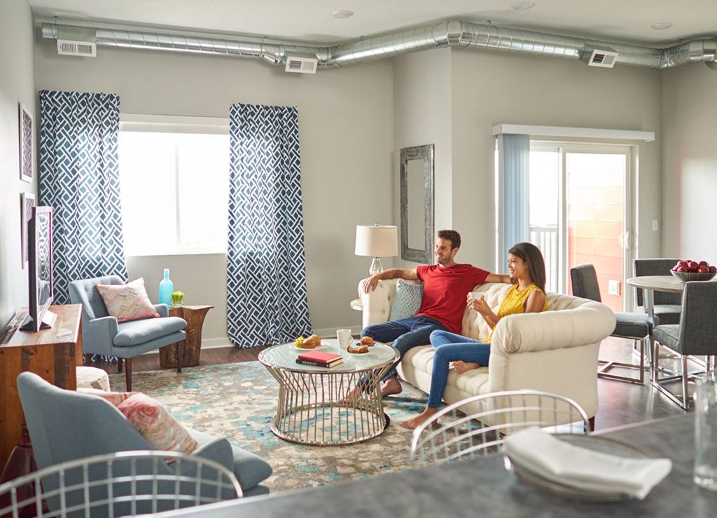 a man and woman sitting on a couch in a living room at Vue Apartments, Iowa, 50309