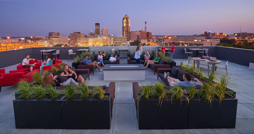 People are sitting on a rooftop with a city skyline in the background at Vue Apartments, Des Moines, IA