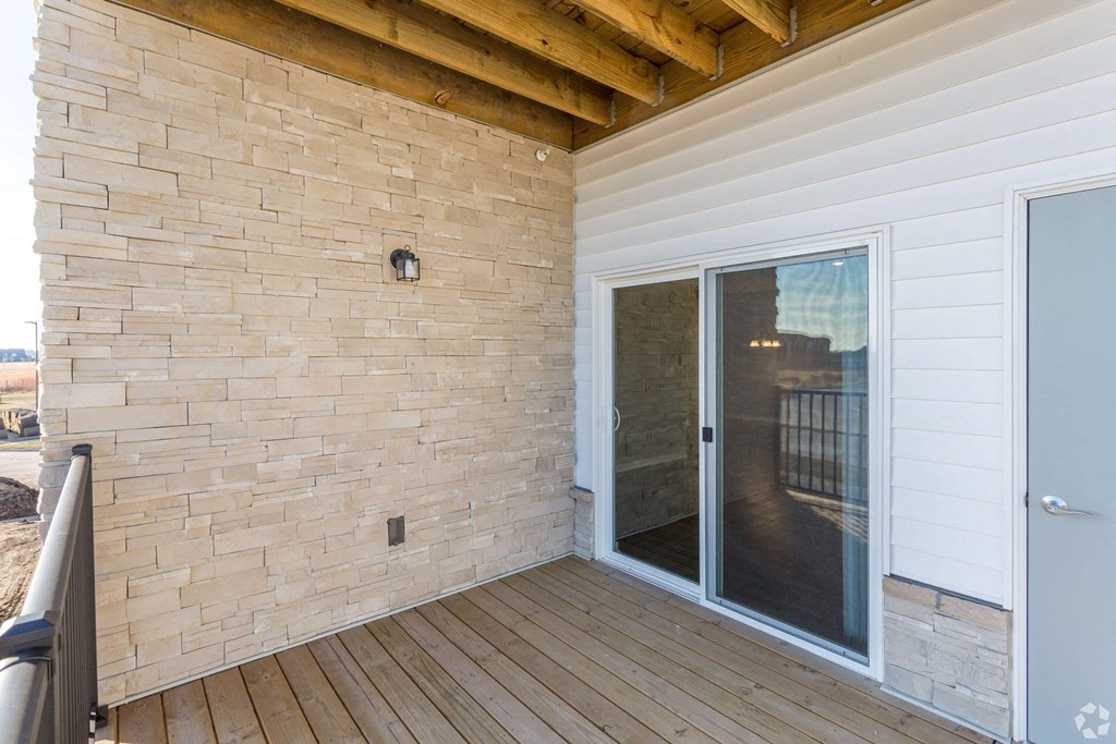 a balcony with a sliding glass door and a brick wall at The Barclay Apartments, Altoona, IA, 50009