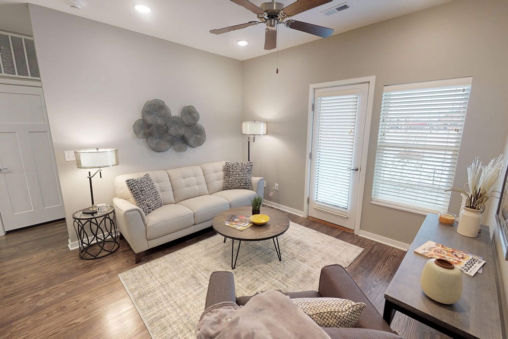 a living room with a couch and a ceiling fan at The Barclay Apartments, Altoona, IA