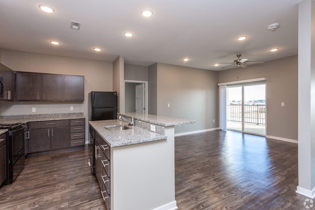 an empty kitchen and living room with a door to a balcony at The Barclay Apartments, Altoona, IOWA