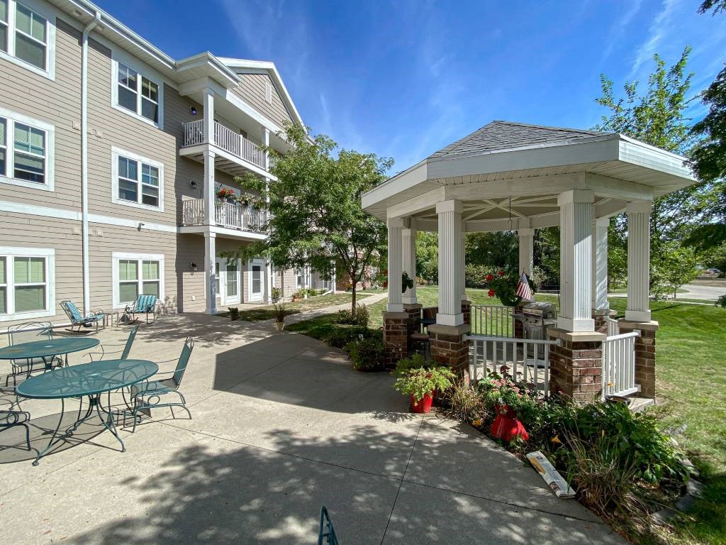 A gazebo is surrounded by a building and a patio with chairs. A gazebo is surrounded by a building and a patio with chairs.at Cornerstone Commons, Johnston, IA 50131
