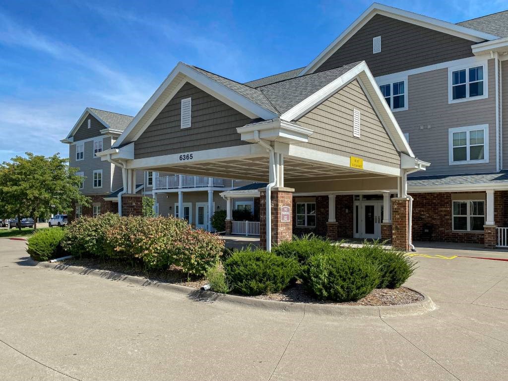 A large building with a covered entrance and a parking lot in front.at Cornerstone Commons, Johnston Iowa  