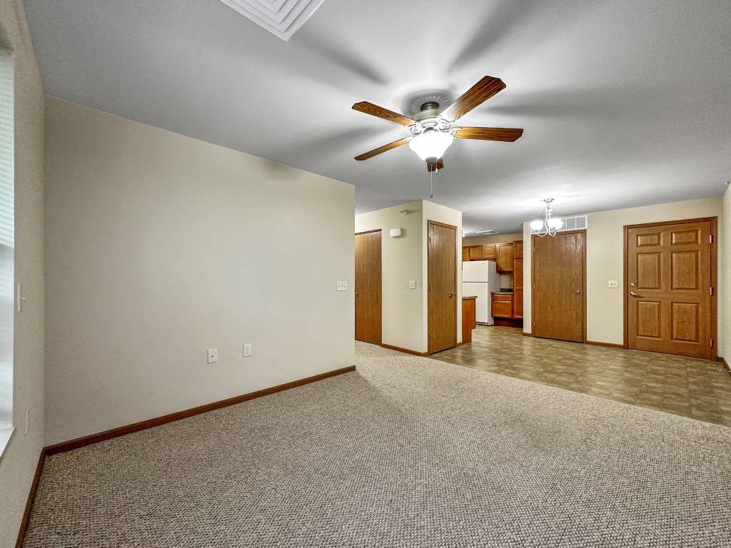 A room with a ceiling fan and carpeted floor.at Cornerstone Commons, Iowa  