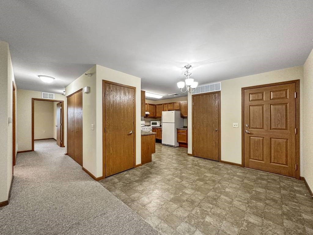 A kitchen area with a refrigerator, sink, and cabinets.at Cornerstone Commons, Johnston  