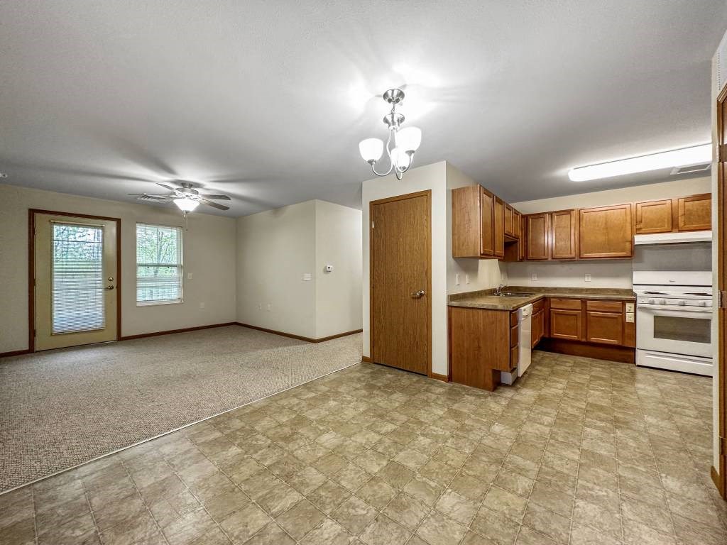 A kitchen with white appliances and wooden cabinets.at Cornerstone Commons, Iowa  