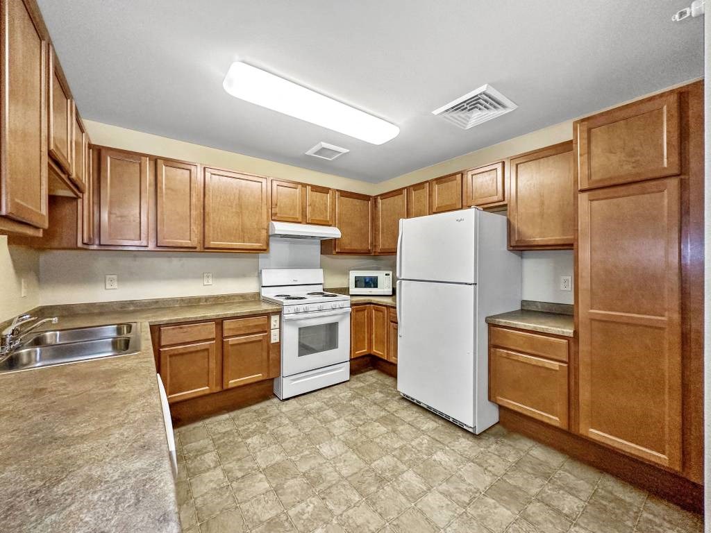 A kitchen with white appliances and wooden cabinets.at Cornerstone Commons, Johnston  
