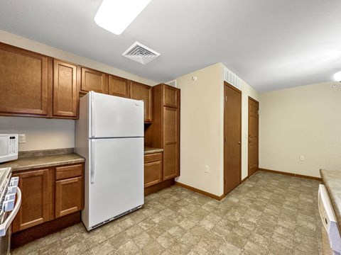 A kitchen with a white refrigerator and brown cabinets.