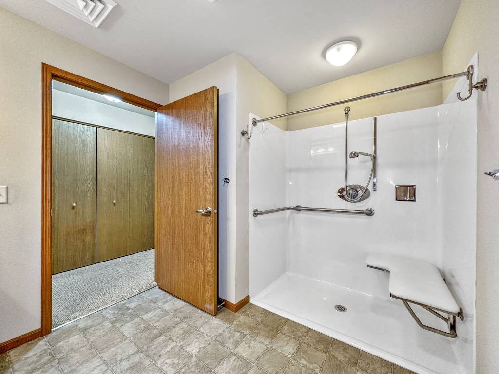A bathroom with a walk-in shower and a wooden door.at Cornerstone Commons, Iowa  