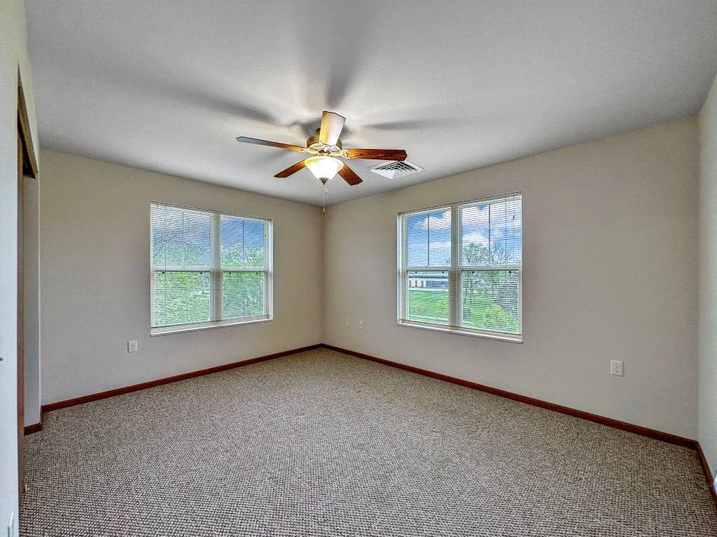 A room with a ceiling fan and two windows.at Cornerstone Commons, Johnston Iowa  