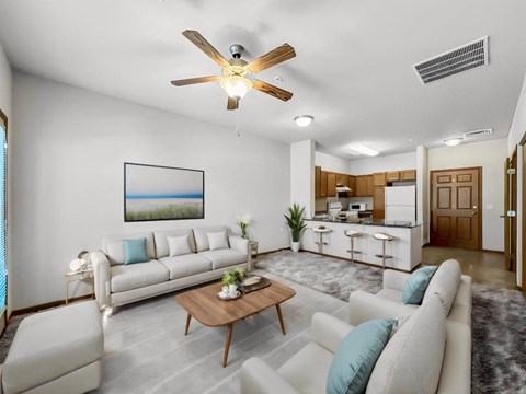 A living room with a white couch, a coffee table, and a ceiling fan.at Cornerstone Commons, Johnston, IA 50131  