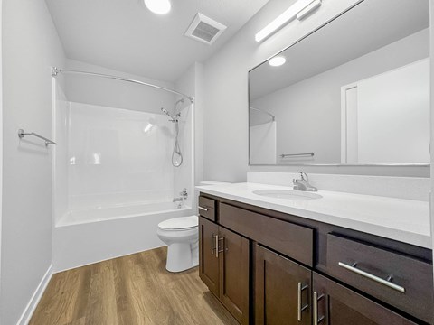 A white bathroom with wooden floors and a white toilet.at Hawthorne Pointe, Bondurant, IA 50035  