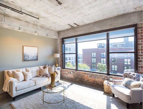 A living room with a white couch and a large window.