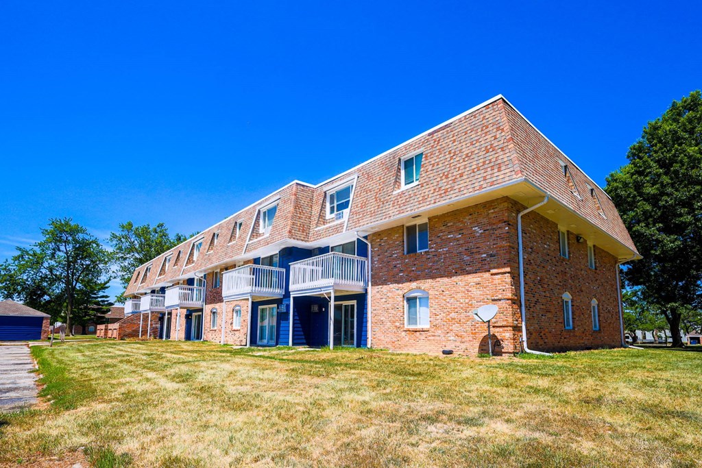 A red brick building with a balcony on the second floor. A red brick building with a balcony on the second floor at The Hampton Meadows Apartments, IA,50315