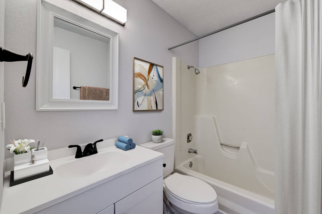 A white bathroom with a white toilet, sink, and bathtub. A white bathroom with a white toilet, sink, and bathtub at The Hampton Meadows Apartments,Des Moines, Iowa