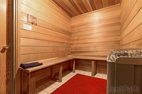 A wooden sauna with a red carpet and benches at The Hampton Meadows Apartments, Iowa
