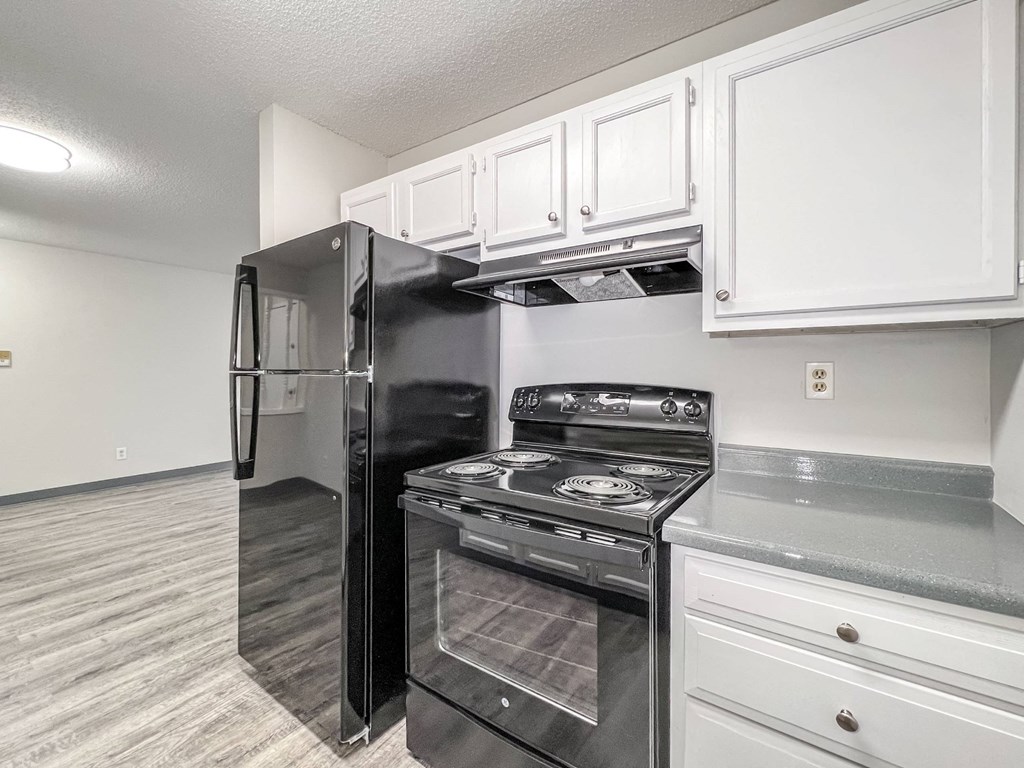 A black refrigerator and stove in a kitchen with white cabinets A black refrigerator and stove in a kitchen with white cabinets at The Ridges Apartments, Des Moines