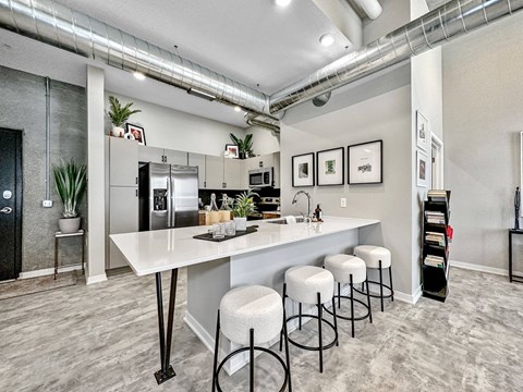 A kitchen with a white counter and bar stools.