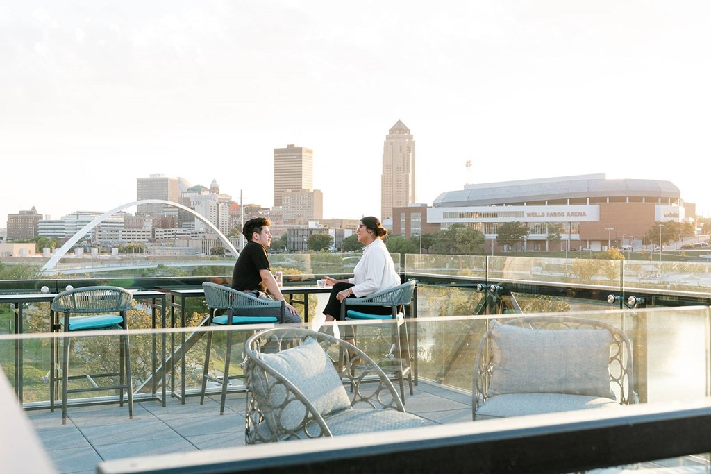 Two people sitting at a table on a balcony overlooking a city skyline.at Level, Des Moines, 50309  