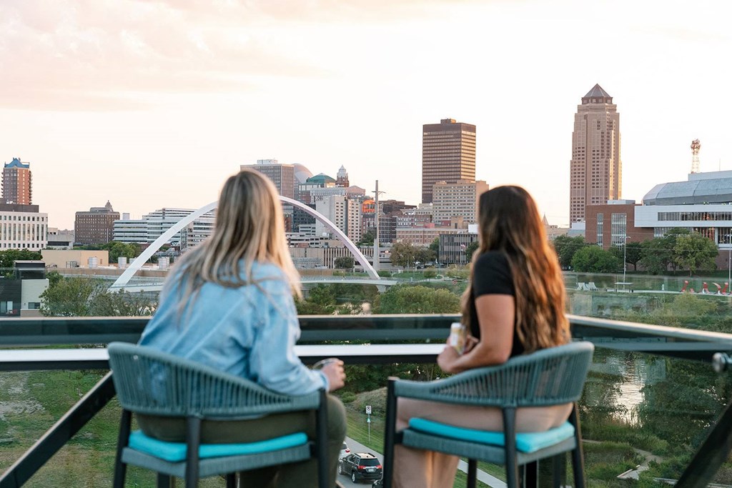 Two women sitting on a balcony overlooking a city skyline.at Level, Des Moines Iowa   