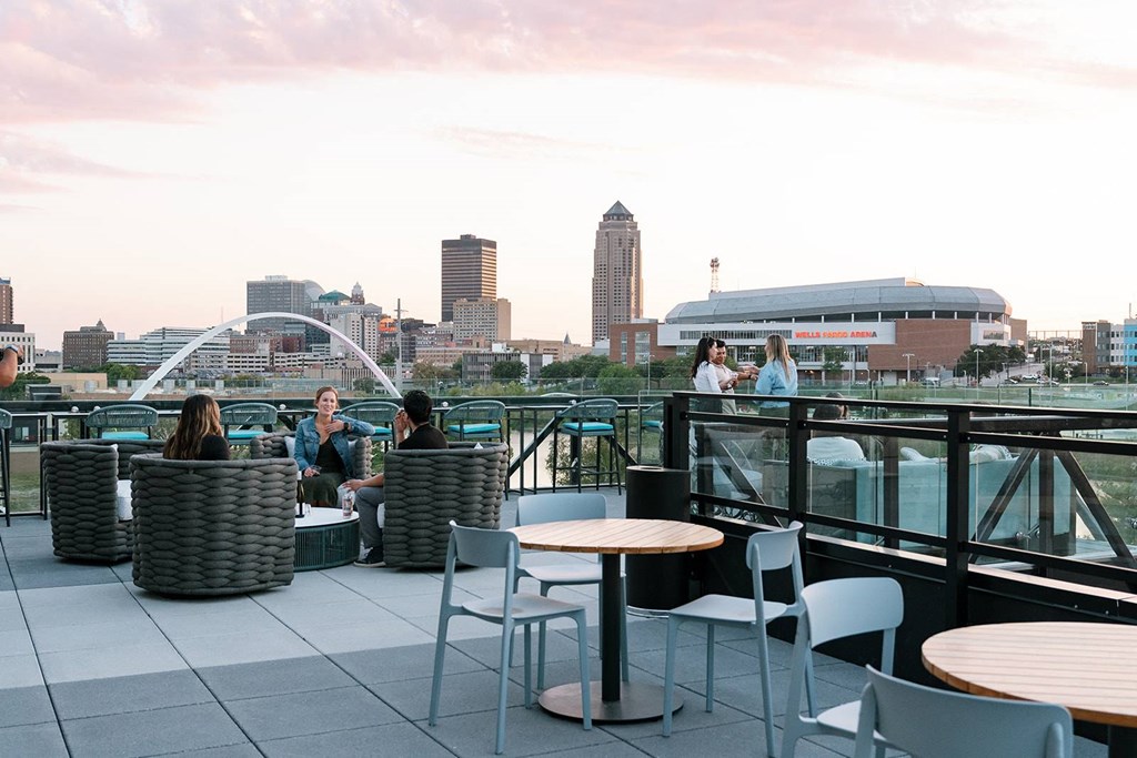 A group of people are sitting on a rooftop terrace with a city skyline in the background.at Level, Des Moines  