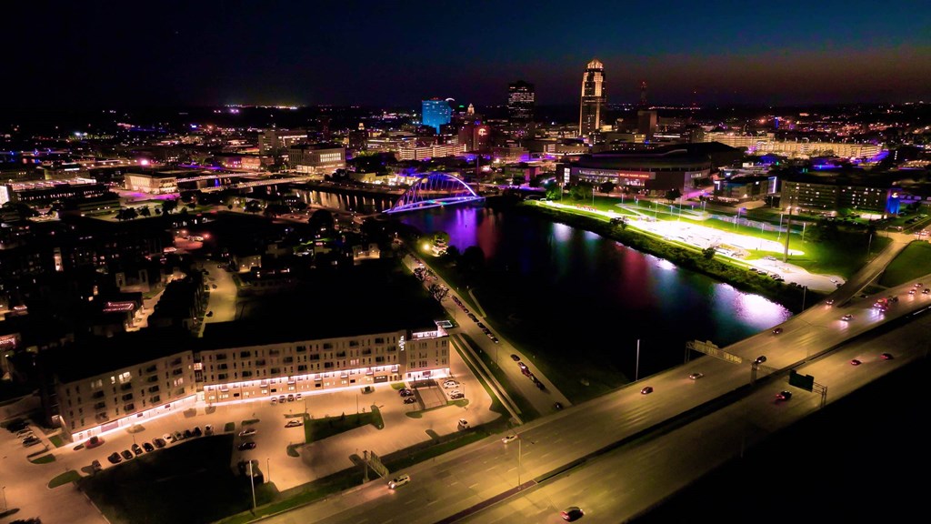 A cityscape at night with a river running through it.at Level, Des Moines, IA 50309  