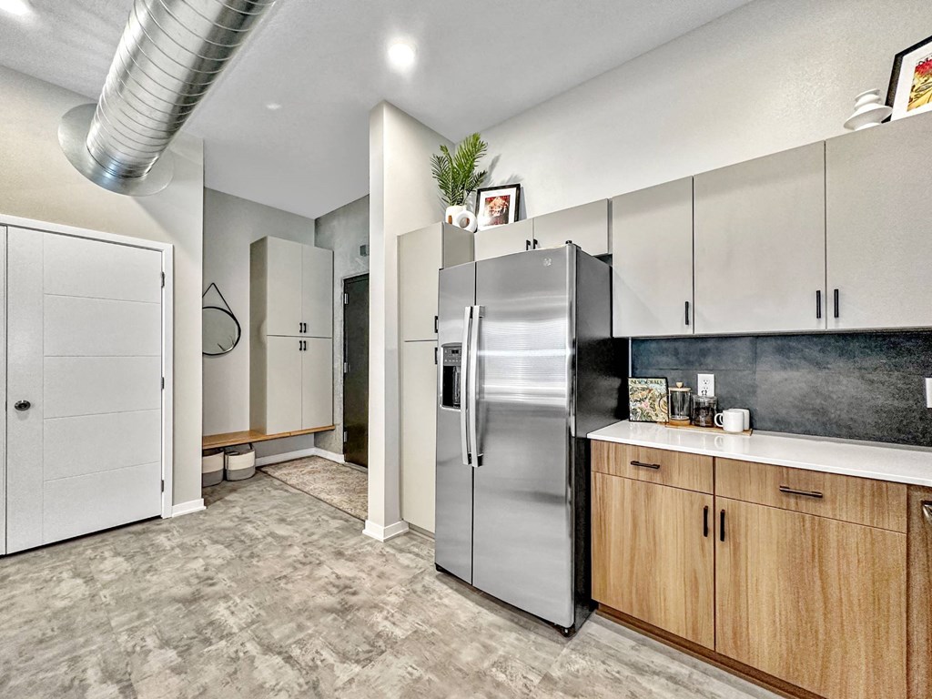A kitchen with a stainless steel refrigerator and wooden cabinets.at Level, Des Moines Iowa   