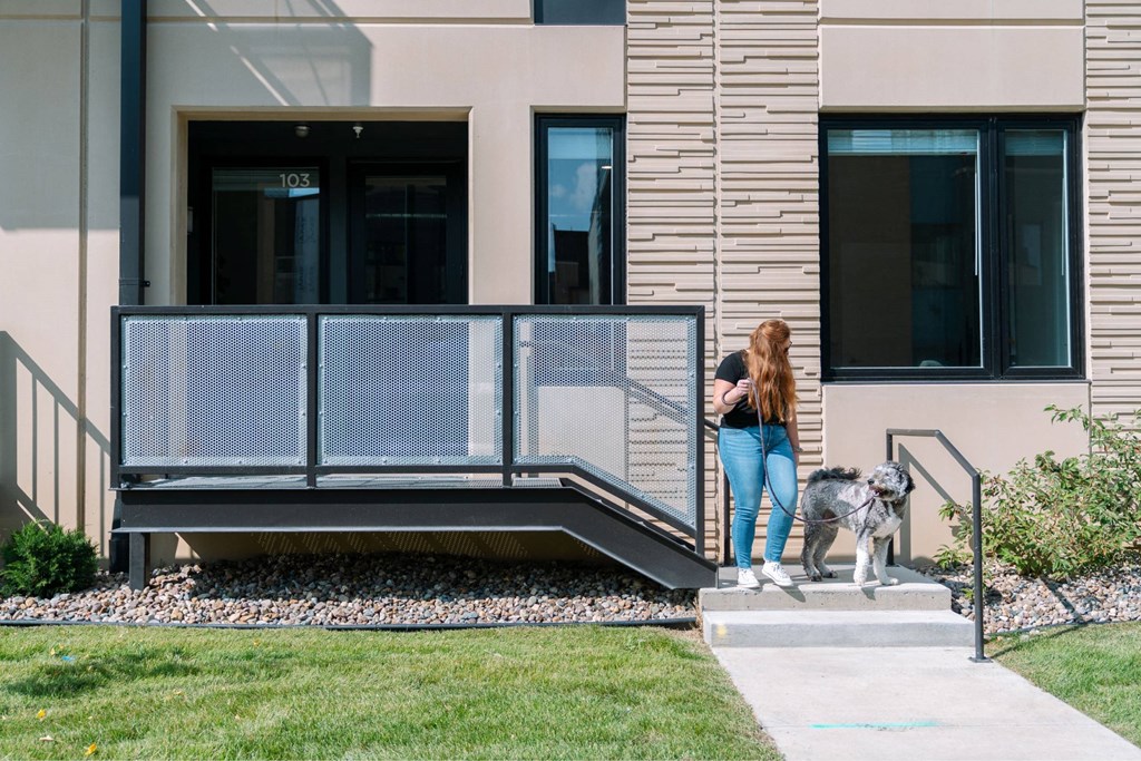 A woman and her dog are standing on a staircase outside a building.at Level, Des Moines, IA 50309  