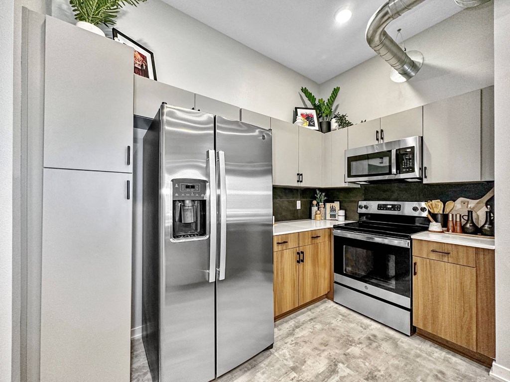 A modern kitchen with a stainless steel refrigerator and wooden cabinets.at Level, Des Moines, IA  