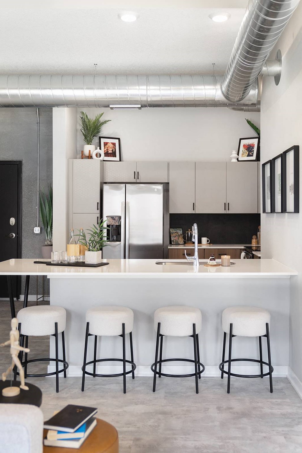 A kitchen with white cabinets and a bar area with white stools.at Level, Iowa   