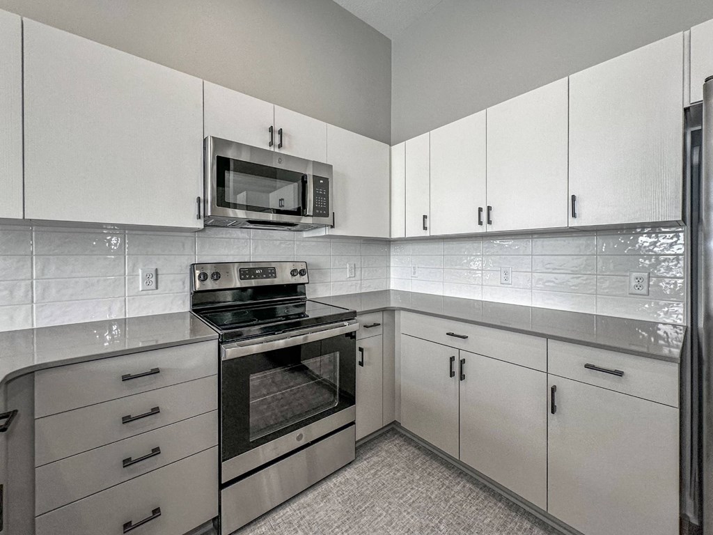 A kitchen with white cabinets and a black stove top oven.at Level, Des Moines  