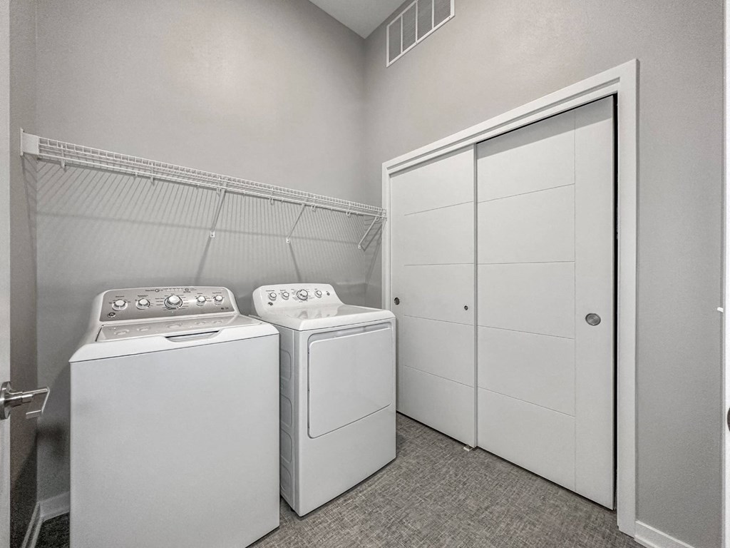 A laundry room with a washer and dryer and a white closet.at Level, Des Moines, IA  