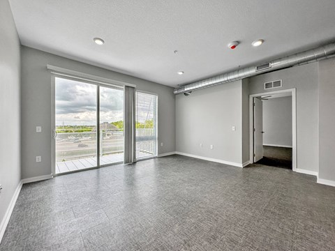 A spacious room with grey carpeting and a view of the outdoors through large windows.at Level, Des Moines Iowa   