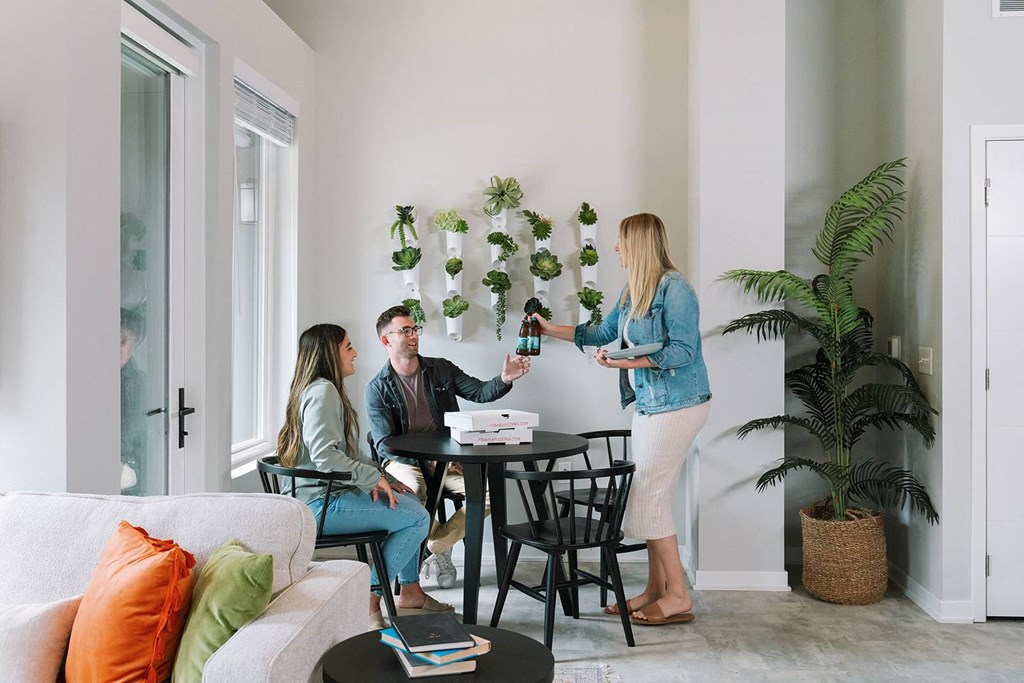 A woman stands in front of a table with two people sitting on chairs.at Level, Iowa, 50309