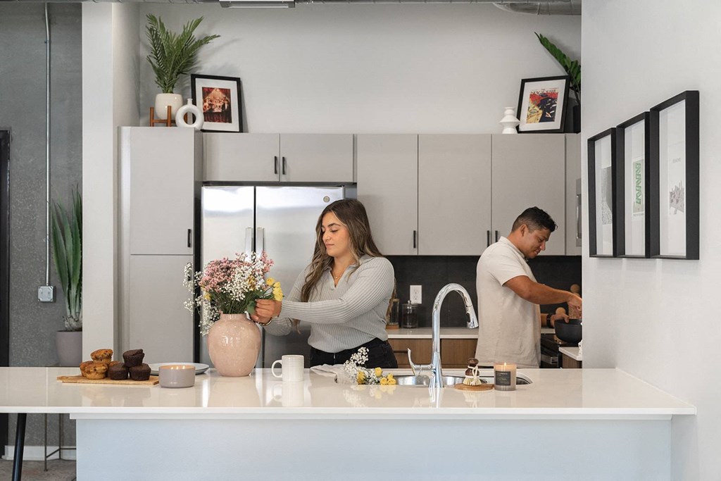 A woman is arranging flowers in a vase on a kitchen counter.at Level, Des Moines, IA 50309  