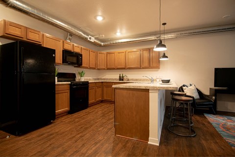 A kitchen with wooden cabinets and a black refrigerator.