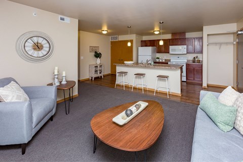 a living room with a couch and a table in front of a kitchen at Melbourne Apartments, Des Moines, IA,  50320