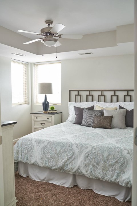 A bedroom with a bed, dresser, and ceiling fan.