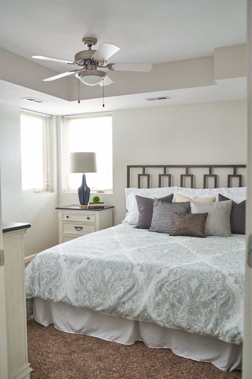 A bedroom with a bed, dresser, and ceiling fan. A bedroom with a bed, dresser, and ceiling fan at Meadowlark Place Apartments, IA, 50111