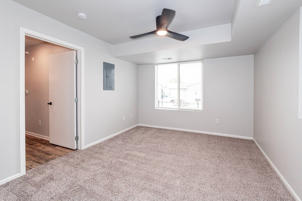 an empty living room with a ceiling fan and a window at Meadowlark Place Apartments, IA, 50111