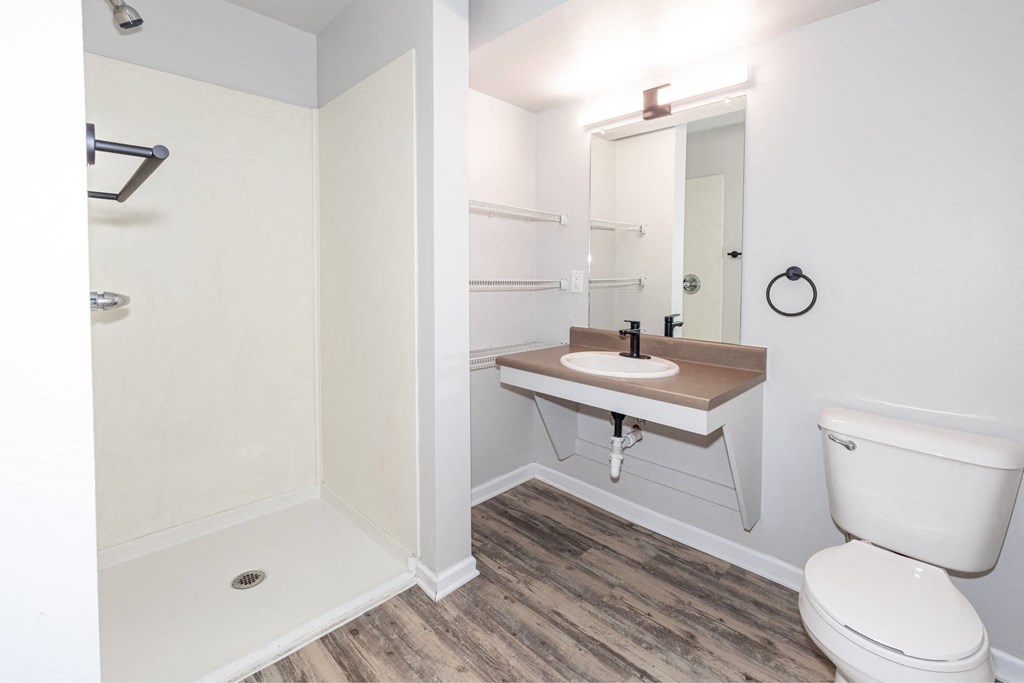 A white toilet sits next to a sink in a small bathroom at Meadowlark Place Apartments, Grimes, IA
